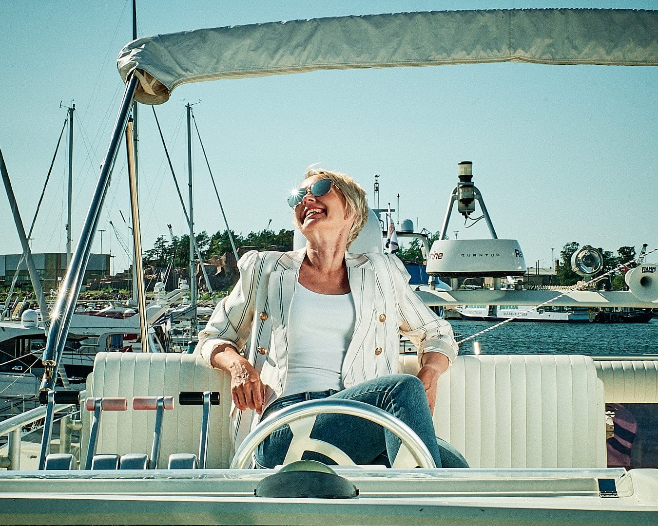 Malou C summer campaign: woman in sunglasses at the helm of a boat in Hanko