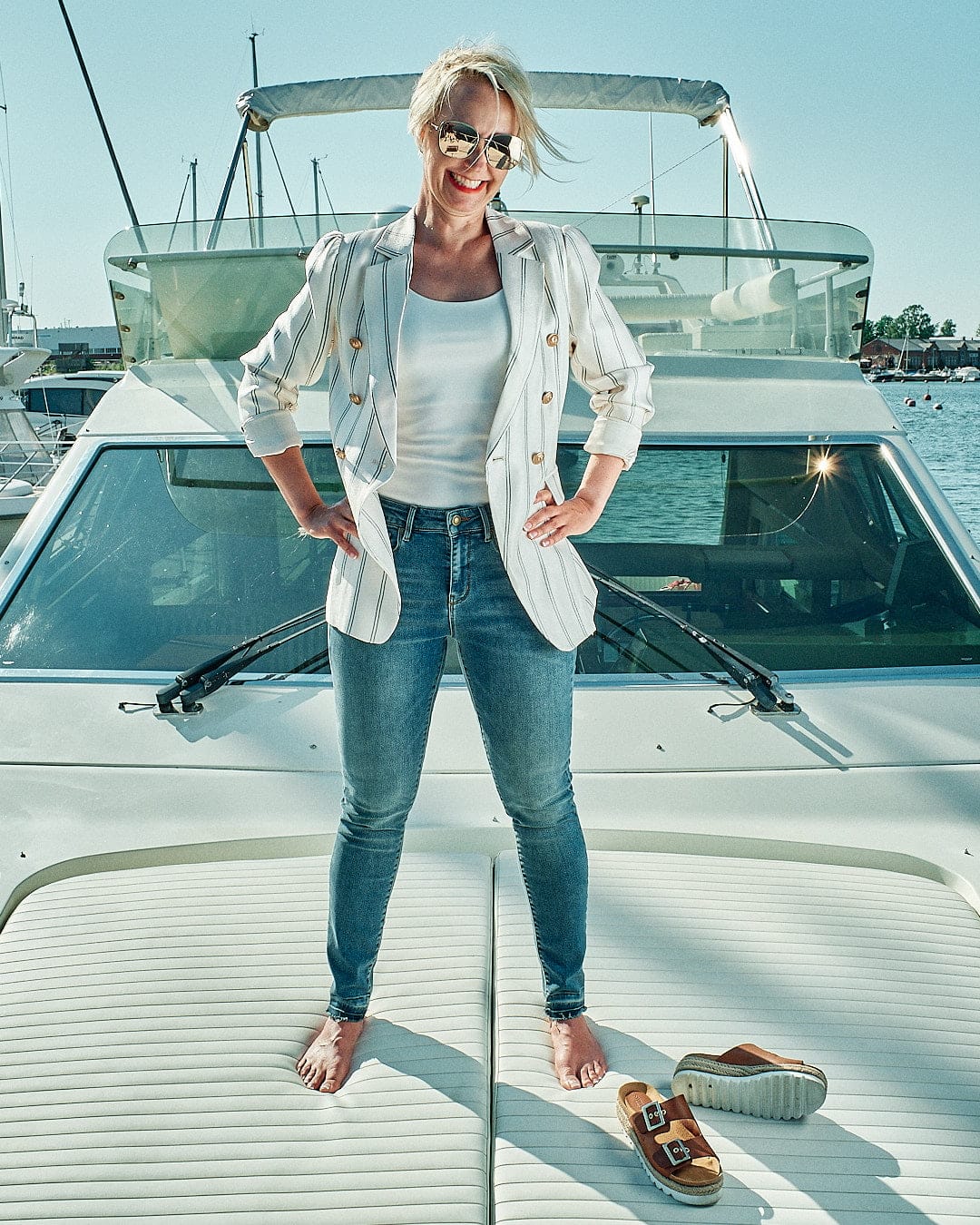 Malou C summer campaign: woman in a striped blazer standing on a boat in Hanko